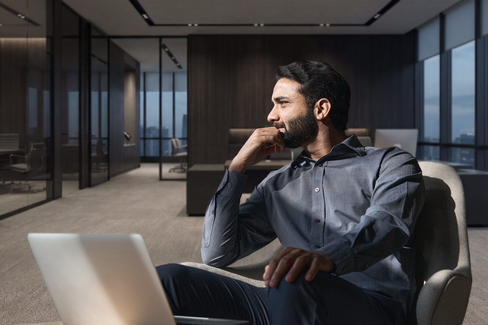 A hiring manager sitting alone in a quiet office, thinking through a decision