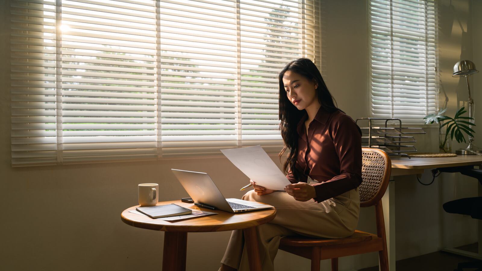 A manager working alone at a table, reviewing printed documents in daylight