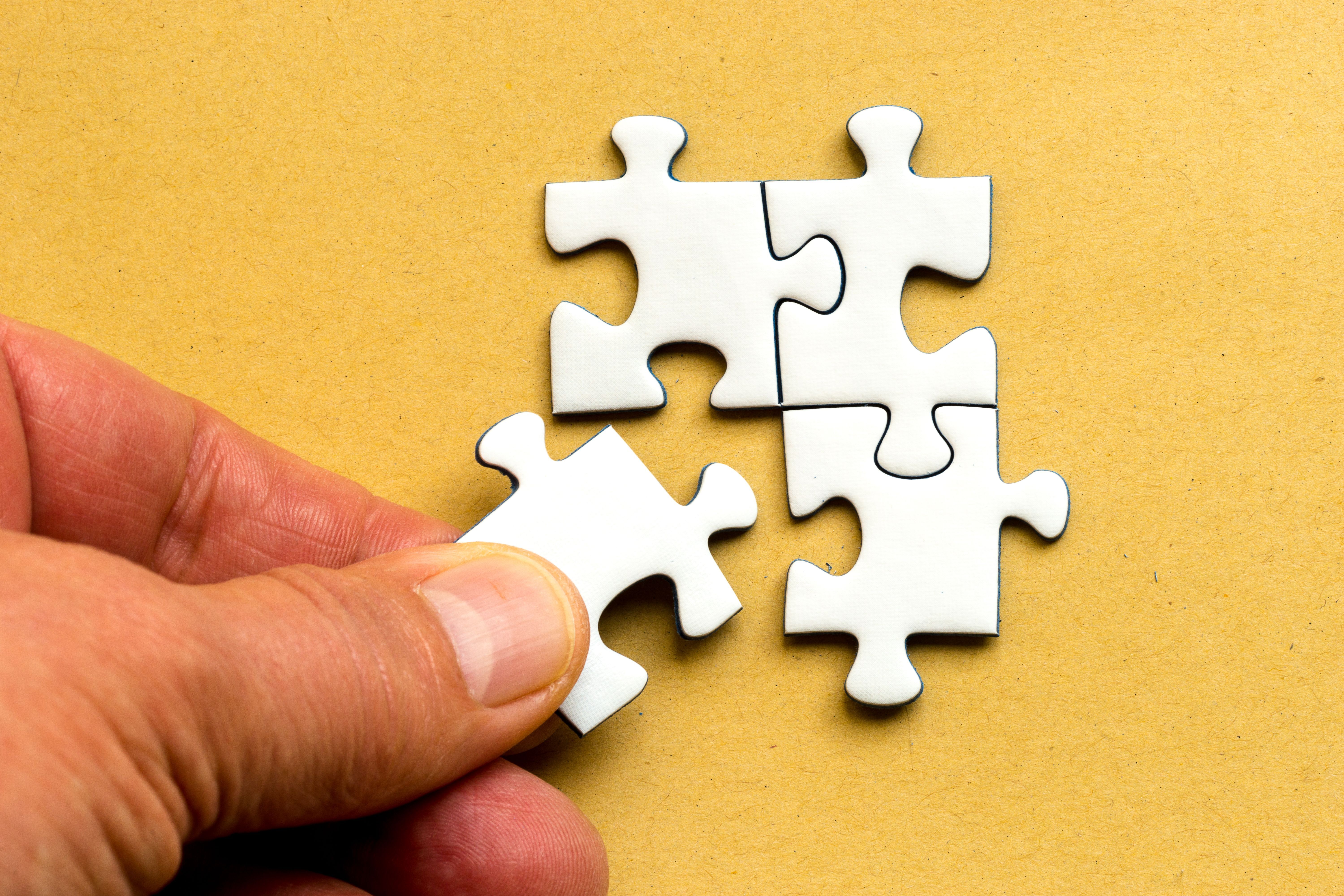 A hand placing the final puzzle piece into place, representing finding the right fit for a role